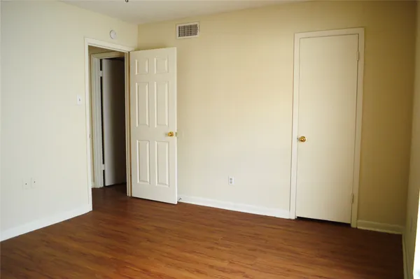 an empty room with wooden floor and closet area