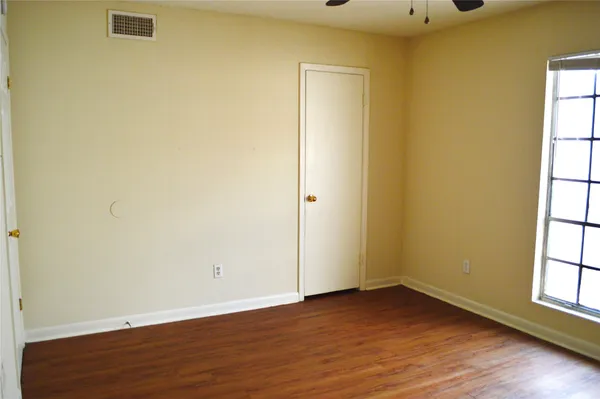 an empty room with wooden floor and windows with curtains