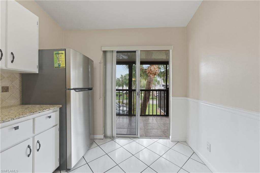4031 Ice Castle Way, Unit 3306 Naples, FL 34112 - Photo 3 of 25 Kitchen featuring white cabinetry, freestanding refrigerator, light tile patterned floors, and backsplash