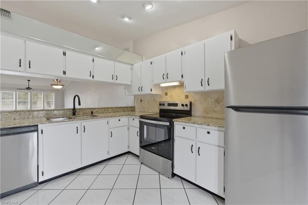 4031 Ice Castle Way, Unit 3306 Naples, FL 34112 - Photo 4 of 25 Kitchen featuring stainless steel appliances, white cabinets, light stone counters, and tasteful backsplash