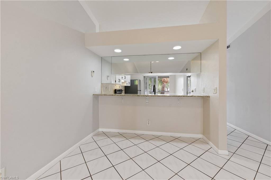 4031 Ice Castle Way, Unit 3306 Naples, FL 34112 - Photo 7 of 25 Kitchen with light stone countertops, white cabinetry, a peninsula, freestanding refrigerator, and recessed lighting