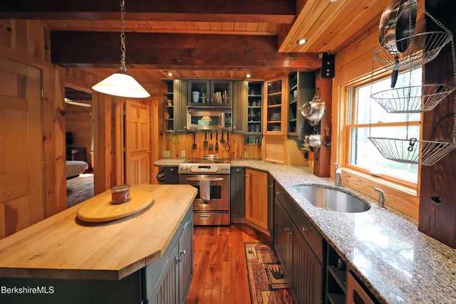 a kitchen with stainless steel appliances granite countertop a sink a stove and a wooden floors