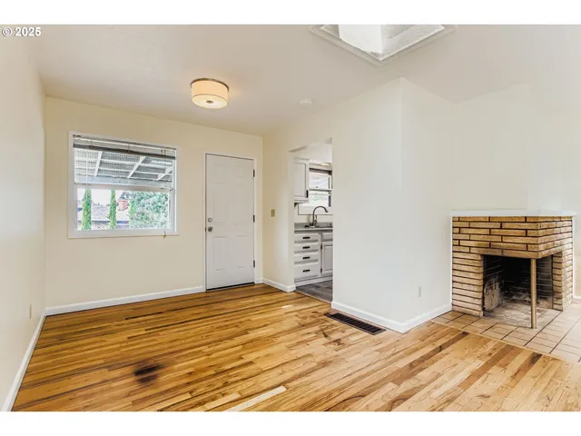 a view of an empty room with a fireplace and a window