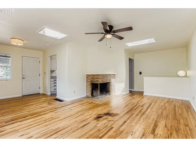 a view of empty room with wooden floor and fireplace