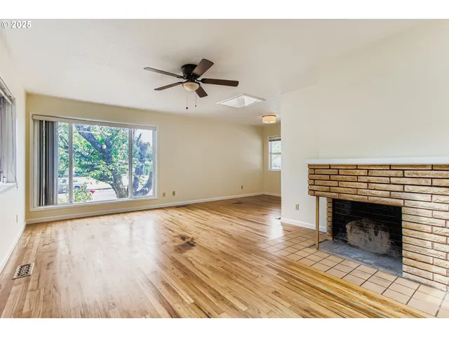 a view of an empty room with a window and wooden floor