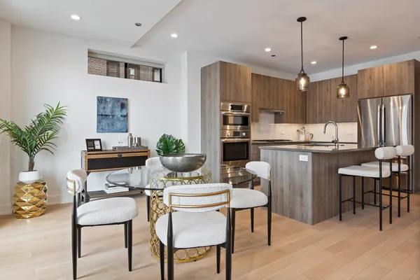 a dining room with stainless steel appliances kitchen island granite countertop a dining table chairs and a refrigerator