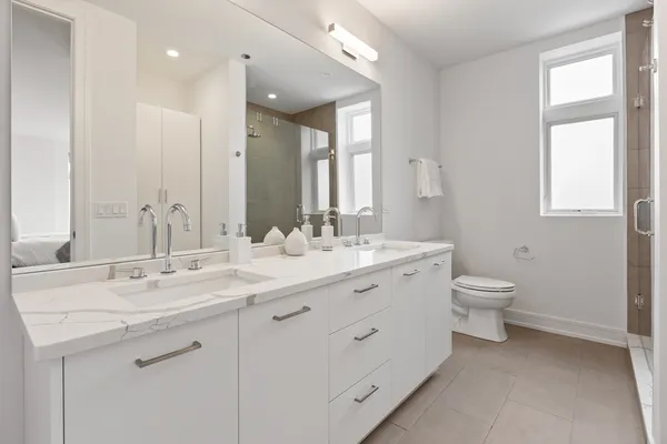 a bathroom with a granite countertop toilet a double vanity sink a mirror and a window