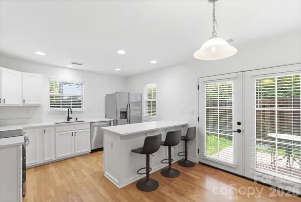 a large kitchen with kitchen island a large window cabinets a sink and stainless steel appliances