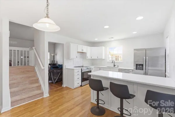 a kitchen with stainless steel appliances kitchen island granite countertop a sink a stove a refrigerator and island with wooden floor