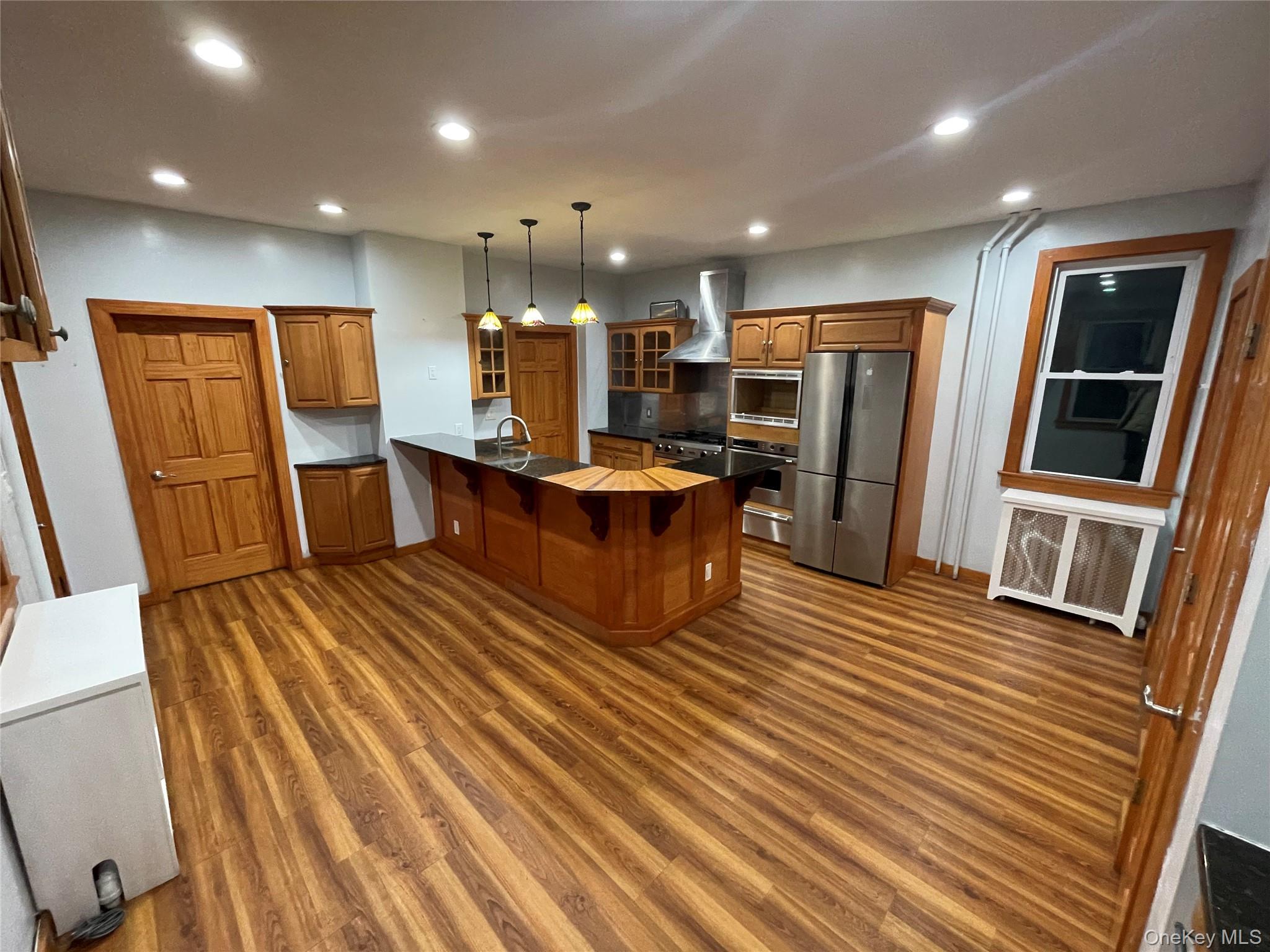Kitchen featuring glass insert cabinets, recessed lighting, a kitchen breakfast bar, a peninsula, and appliances with stainless steel finishes