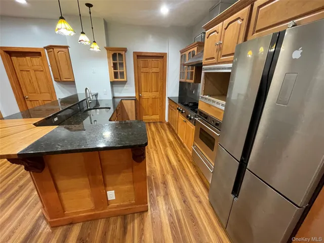 a kitchen with stainless steel appliances granite countertop a refrigerator a stove and a sink with wooden floor