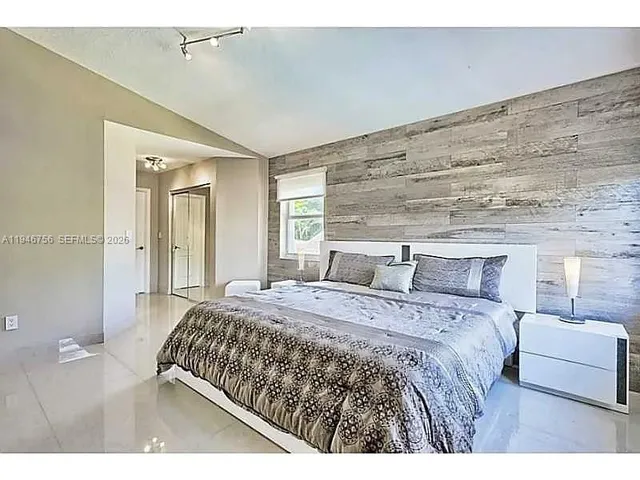 a bedroom with a bed a mirror and a night stand