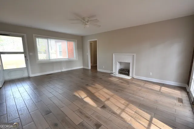 a view of an empty room with wooden floor and a window