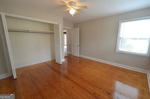 an empty room with wooden floor closet and windows