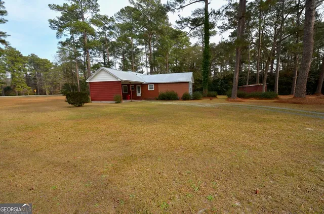 a view of a house with a yard and large trees