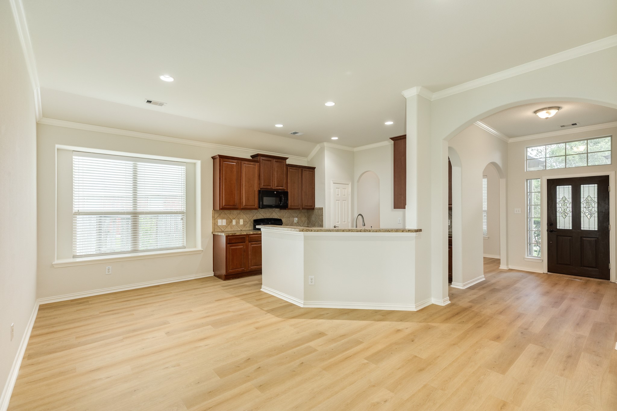 13417 Star Creek Lane Rosharon, TX 77583 - Photo 41 of 41 This photo showcases a spacious, open floor plan. The view is from the family area, offering a glimpse of the kitchen and front door.