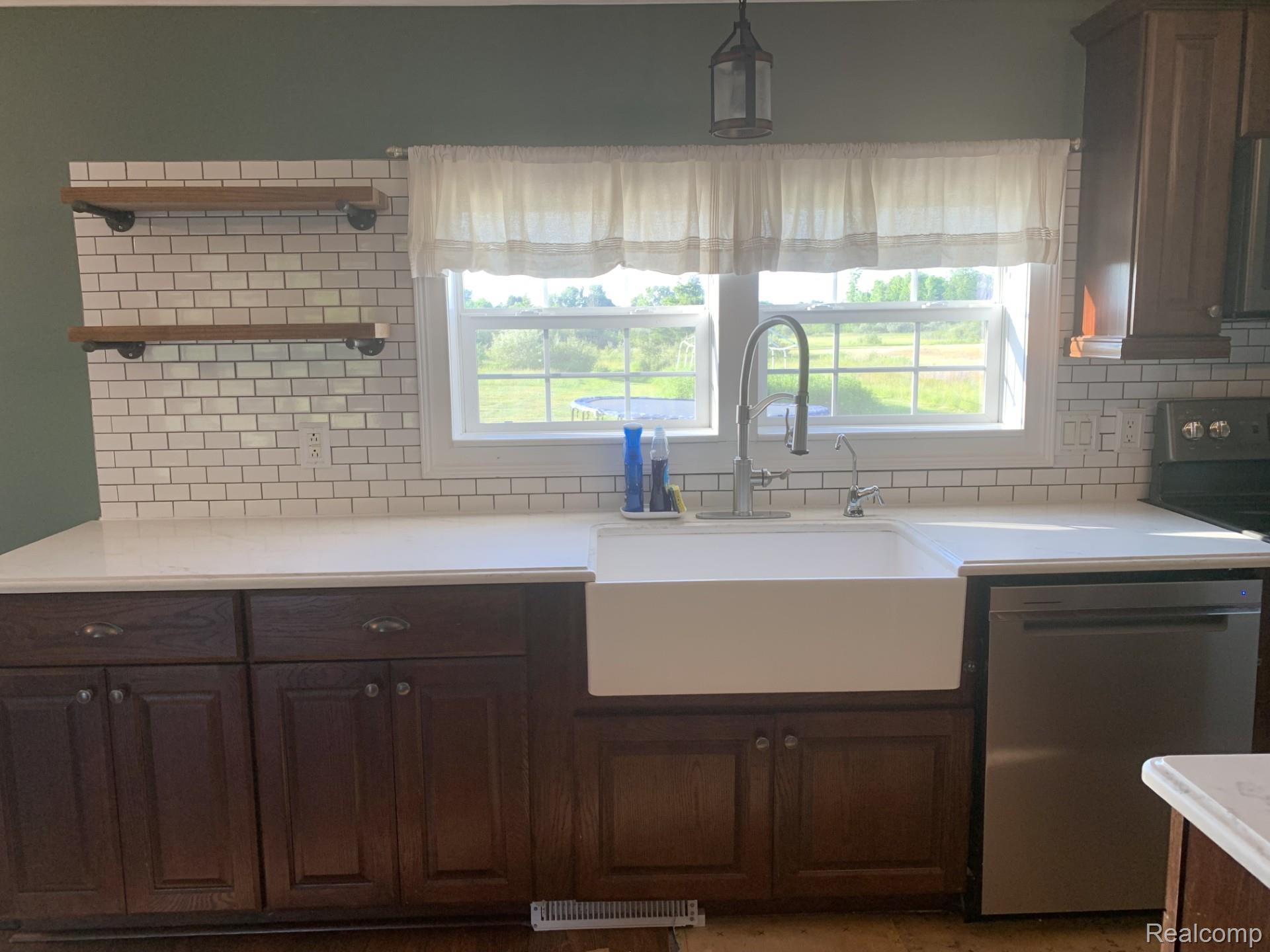 4168 Harris Road Fort Gratiot, MI 48059 - Photo 13 of 30 Kitchen featuring a white farmhouse sink, stainless steel faucet, subway tile backsplash, white countertops, and dark wood cabinetry