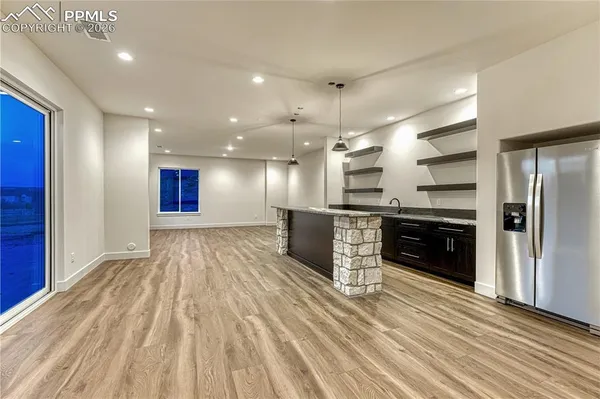 a kitchen with stainless steel appliances kitchen island granite countertop a refrigerator oven a sink and dishwasher with wooden floor