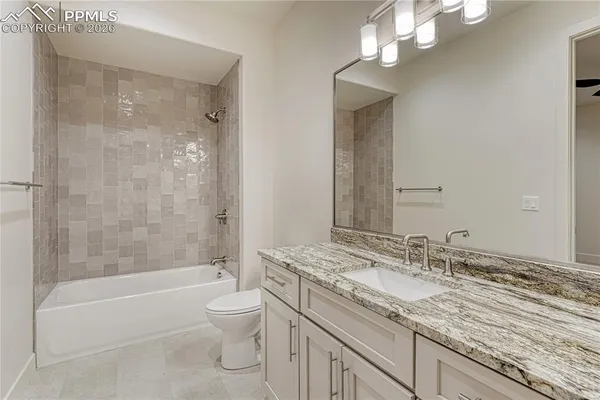 a bathroom with a granite countertop sink a toilet and bathtub
