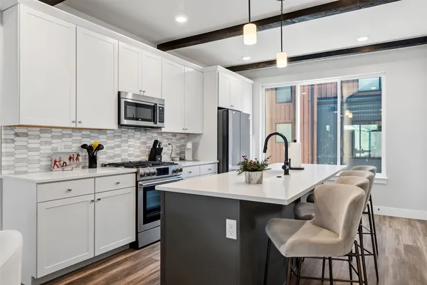 a kitchen with stainless steel appliances granite countertop a stove a sink dishwasher a microwave oven with a dining table and chairs