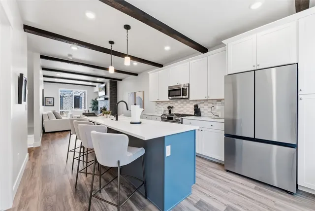 a kitchen with stainless steel appliances a refrigerator a sink dishwasher a stove and white countertops with wooden floor