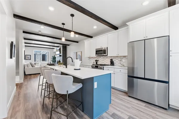 a kitchen with stainless steel appliances a refrigerator a sink dishwasher a stove and white countertops with wooden floor