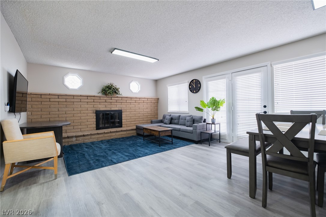 6356 West Viking Road Las Vegas, NV 89103 - Photo 6 of 51 An open living space highlights a classic brick fireplace and durable wood-look flooring.
