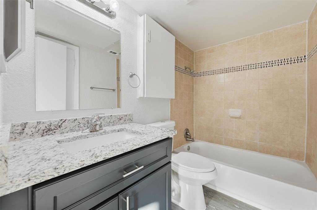 2702 Douglas Avenue, Unit 121 Dallas, TX 75219 - Photo 23 of 34 a bathroom with a granite countertop sink a toilet a mirror and shower