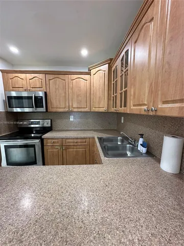 a kitchen with granite countertop a stove a sink and a microwave