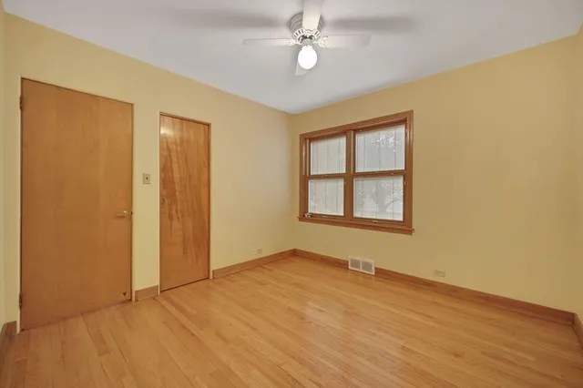 a view of an empty room with window and wooden floor