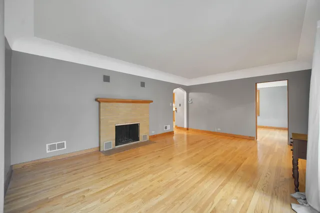 a view of empty room with wooden floor and fireplace