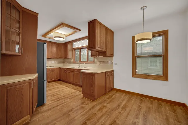 a kitchen with kitchen island granite countertop wooden cabinets a sink a stove and a wooden floor