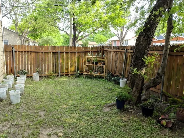 a view of a backyard with wooden fence and a large tree