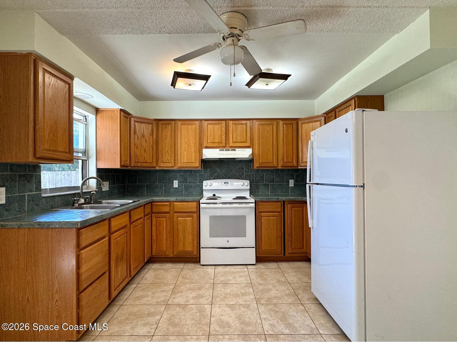 518 Sylvia Road Melbourne, FL 32904 - Photo 3 of 18 a kitchen with stainless steel appliances granite countertop a refrigerator a sink dishwasher a stove with wooden cabinets and floor