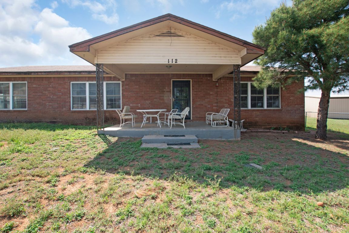 Front  of house featuring a yard, brick siding, fence, and a patio