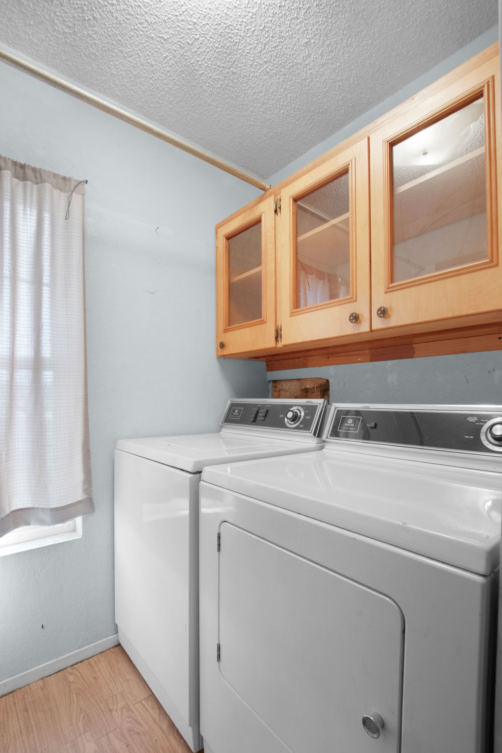 112 Frazier Tow, TX 78672 - Photo 18 of 30 Laundry room featuring light wood finished floors, washing machine and clothes dryer, a textured ceiling, baseboards, and cabinet space