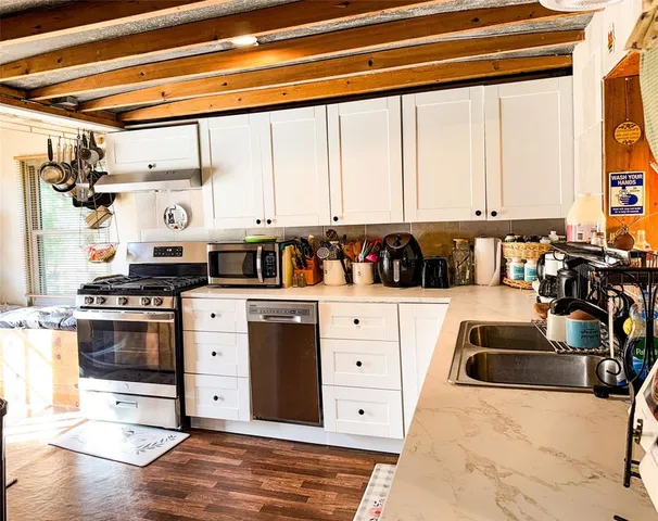 a kitchen with stainless steel appliances kitchen island granite countertop a sink and white cabinets
