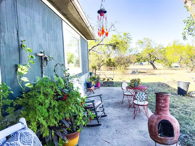 a backyard of a house with table and chairs plants