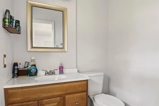 a bathroom with a toilet sink vanity and mirror