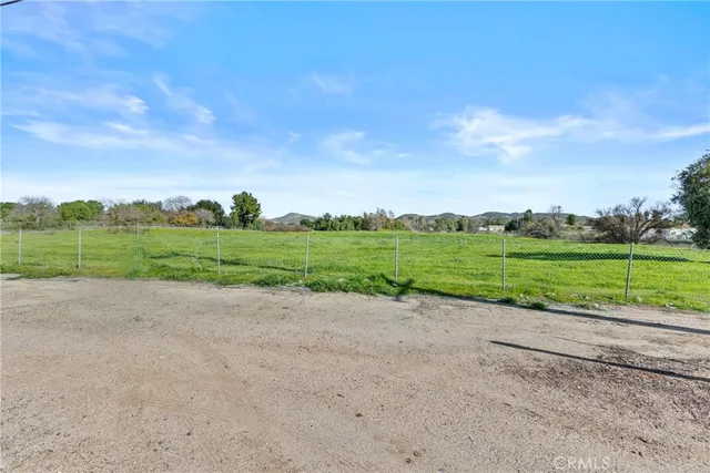 a view of a green field with wooden fence