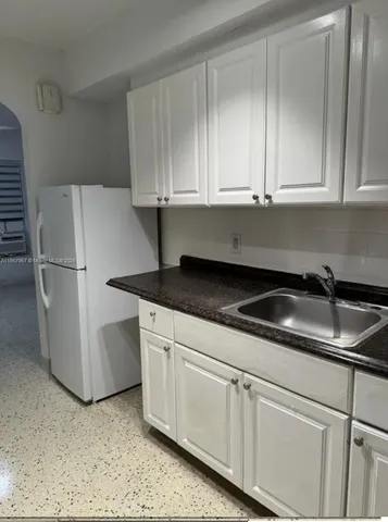 a kitchen with granite countertop white cabinets and sink