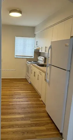 a kitchen with cabinets appliances and a wooden floor
