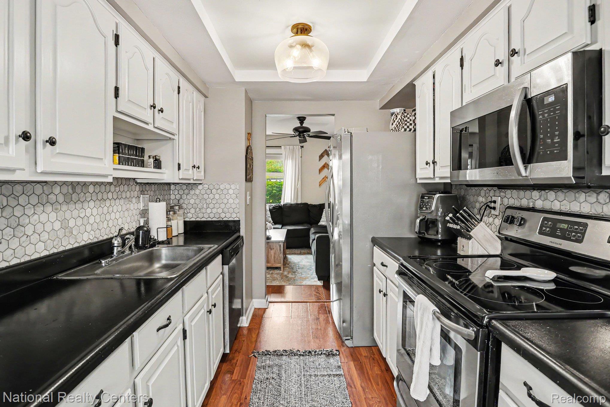 753 Oak Brook Ridge Drive Rochester, MI 48307 - Photo 6 of 18 Kitchen featuring stainless steel appliances, dark countertops, white cabinets, and a raised ceiling