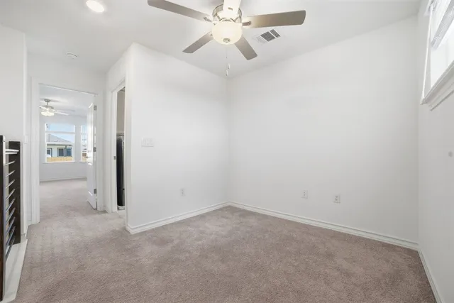 an empty room with staircase and ceiling fan