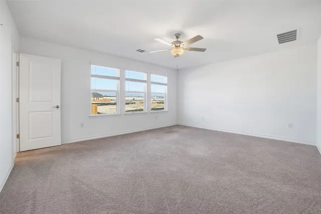 an empty room with windows and fan