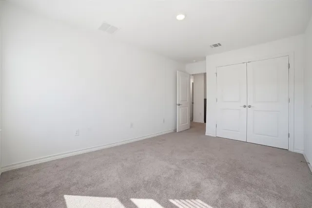 an empty room with chandelier fan and windows