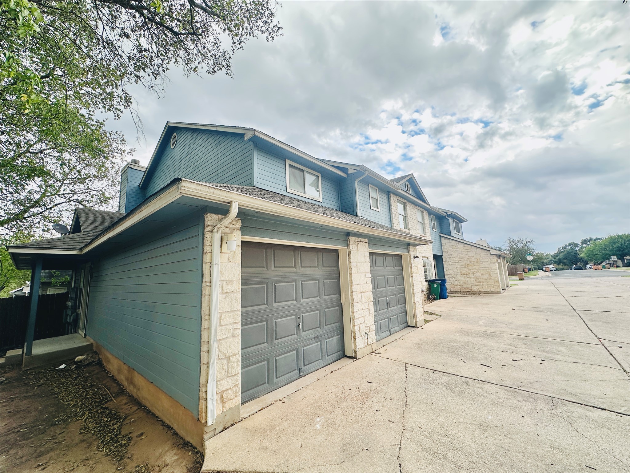 8814 Schick Road, Unit D Austin, TX 78729 - Photo 1 of 1 View of home's exterior with a garage, concrete driveway, roof with shingles, and stone siding