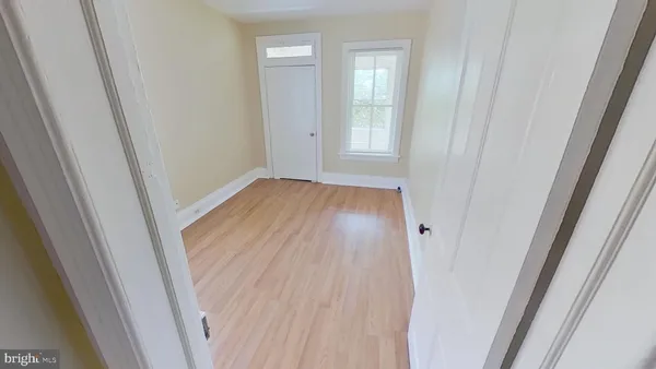 a view of empty room with wooden floor and entryway