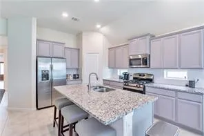 a kitchen with kitchen island granite countertop a sink stove and refrigerator