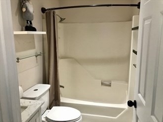 1619 Braley Road, Unit 98 New Bedford, MA 02745 - Photo 28 of 32 a white toilet sitting next to a bathroom sink and a shower